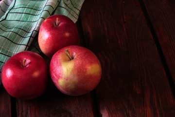 A few red ripe apples on an old dark wooden table