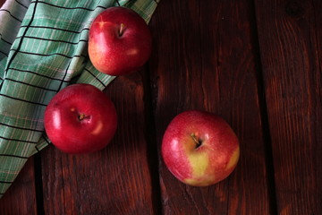 A few red ripe apples on an old dark wooden table