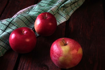 A few red ripe apples on an old dark wooden table