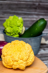 Chou-fleur jaune aubergine courgette chou romanesco sur une planche à découper, légumes bio du jardin