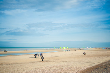 people in autumn at the beach on a sunny day with sailing cars in the background