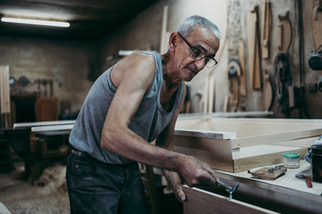 Close up shot of old master carpenter working in his woodwork or workshop. Traditional craftsmanship concept.