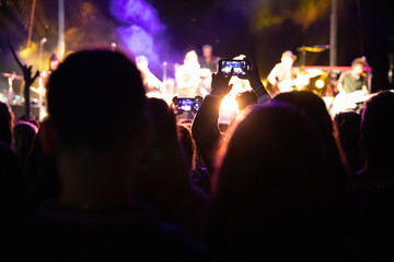El público graba su teléfono inteligente un concierto musical por la noche