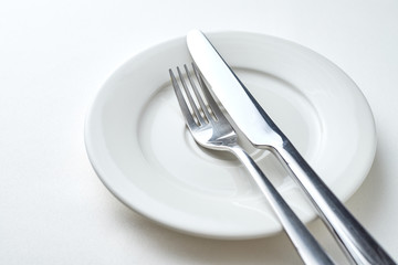 Fork and knife on a white plate on a white background