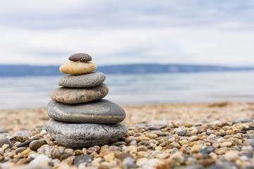 Stones balances on the beach of blue sea with mountain
