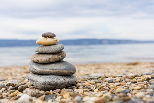 Stones balances on the beach of blue sea with mountain