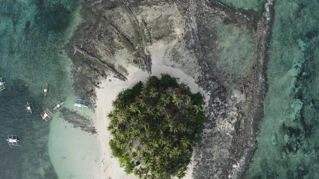 4K Aerial Drone Footage Rotating Over a Tropical Island in the Philippines named Guyam near Siargao. Ithas lush palm trees and white sandy beaches with a rocky shore line