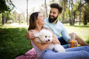 Lifestyle, happy couple resting at a picnic in the park with a dog