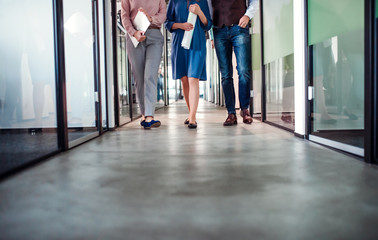 Midsection of group of business people walking in an office building.