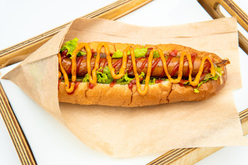 Hot dog with salad and cucumbers with tomato ketchup and mustard on white background. Tasty and beautiful fast food on a light back.