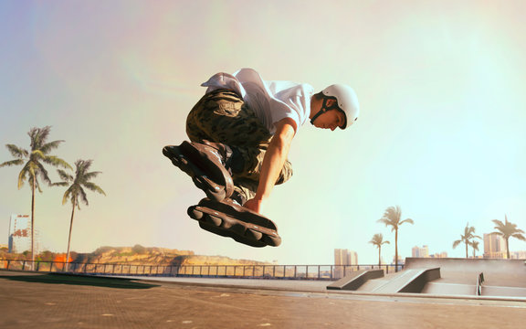 Rollerskater man is performing tricks in skatepark on sunset.