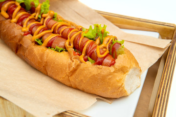 Hot dog with salad and cucumbers with tomato ketchup and mustard on white background. Tasty and beautiful fast food on a light back.