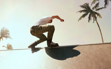 Rollerskater man is performing tricks in skatepark on sunset.