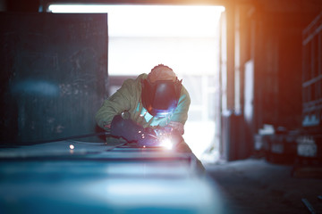 A welder with a welding machine works in a factory