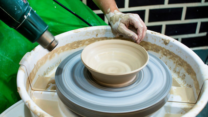 Fototapeta premium A raw clay pot in the hands of a potter. Workshop in the pottery workshop. Clay pot on a potter`s wheel