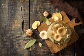 Fermented food: Mushroom preservation. Home preservation of products: glass jars with pickled mushrooms with spices on a rustic wooden table.  Top view flat lay. Free space for your text.