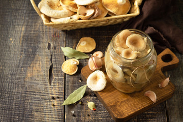 Fermented food: Mushroom preservation. Home preservation of products: glass jars with pickled mushrooms with spices on a rustic wooden table. Free space for your text.
