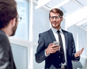 businessman with a smartphone standing in his ofiice