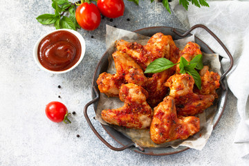 Tasty snack. Baked chicken wings with mustard tomato sauce on a concrete table.