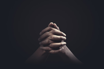 Praying hands with faith in religion and belief in God on dark background. Power of hope or love...