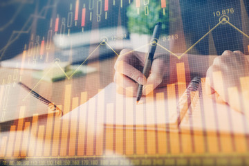 Financial forex graph drawn over hands taking notes background. Concept of research. Multi exposure