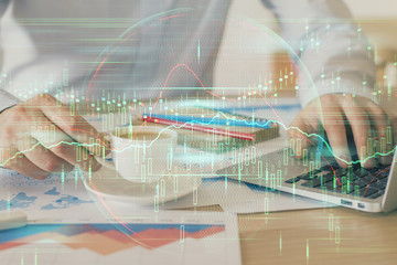 Forex graph with businessman working on computer in office on background. Concept of hardworking. Double exposure.