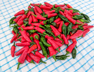 Red and green chilli peppers. Large fresh pile on a kitchen tea towel background.