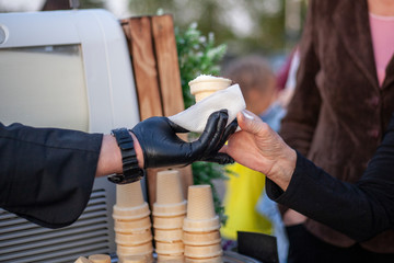 Making ice cream on the street. Waffle cup in the hand of an ice cream maker. Sweetness from milk. Filling a wafer cup with cream.