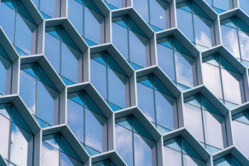 Office buildings. Structure of hexagon windows in futuristic technology network connection concept. Blue glass modern architecture facade design with reflection of sky in urban city, Downtown. - Powered by Adobe