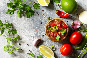 Traditional Latin American mexican salsa sauce with ingredients on a light stone table. Top view flat lay.
