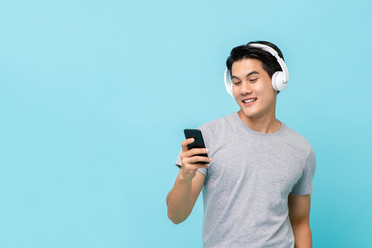 Asian man wearing headphones listening to music from smartphone