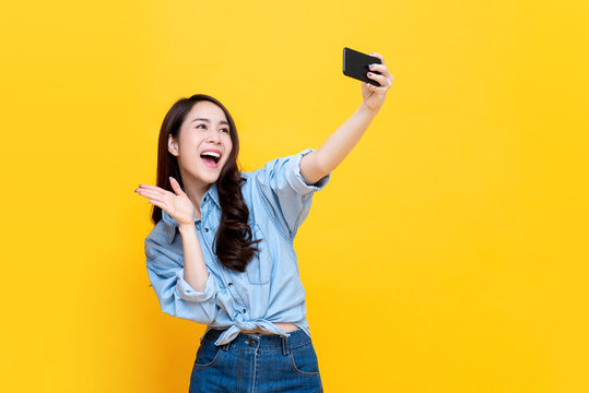 Asian Woman Taking Selfie Isolaed On Yellow Background