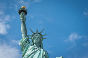 Fototapeta premium Shot of the Statue of Liberty in New York City, Usa. The shot is taken during a beautiful sunny day with a blue sky and white clouds in the background 
