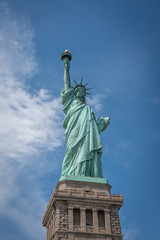 Fototapeta premium Shot of the Statue of Liberty in New York City, Usa. The shot is taken during a beautiful sunny day with a blue sky and white clouds in the background 
