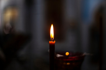 Wax candle flame. The candle burns in the dark. Bright light from felit. Red fire. Religious rite with a candle.