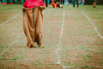 People running sack race in field in culture of countryside 