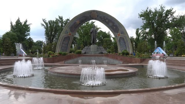 Dushanbe Abu Abdullah Rudaki Park Statue Frontal View with Fountains and Walking People on a Cloudy Rainy Day
