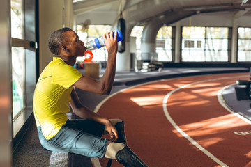 Athlete drinking water by running track