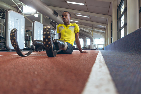 Disabled African American male athletic relaxing on a running track in fitness center