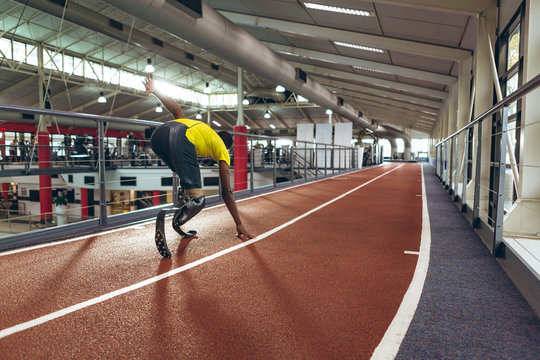 Disabled African American male athletic running on race track in fitness center