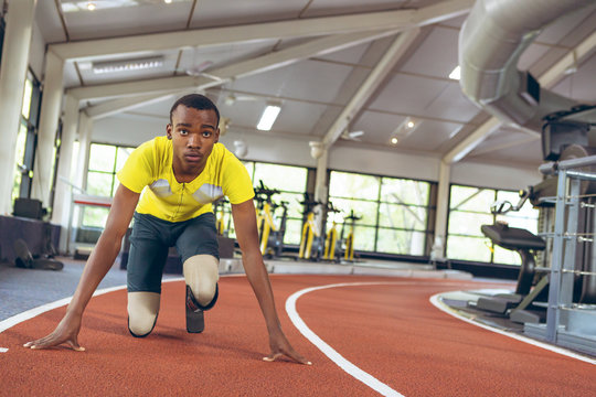 Disabled African American male athletic in starting position on running track in fitness center