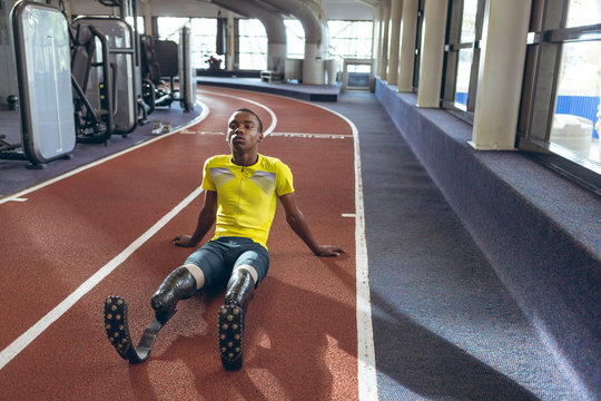Disabled African American male athletic relaxing on a running track in fitness center