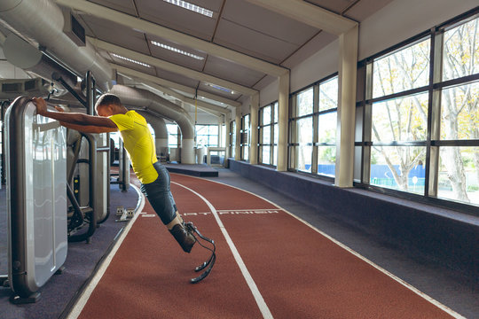 Disabled African American male athletic exercising on running track in fitness center