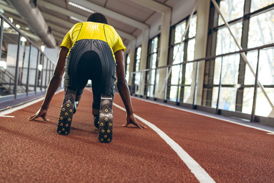 Disabled African American male athletic in starting position on running track in fitness center
