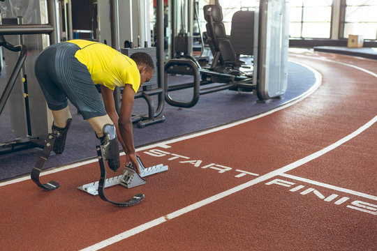 Disabled African American male athletic at starting block on running track in fitness center
