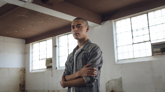Young man inside an empty warehouse with arms crossed