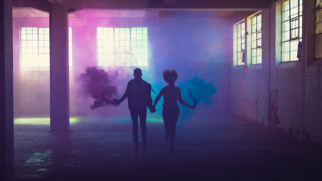 Couple running with distress flares in industrial building