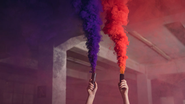 Man's hand holding smoke bomb in empty warehouse