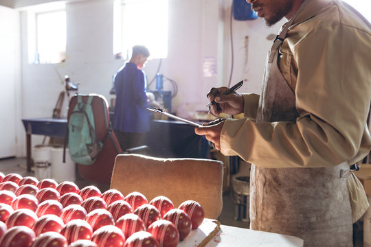 Young man writing on clipboard in factory