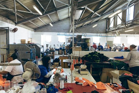 Women using sewing machines and sorting fabric in a clothing factory